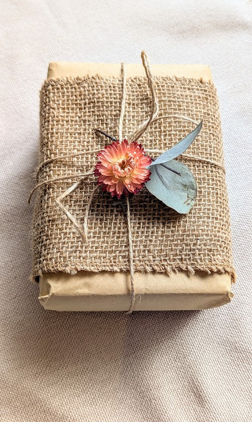 Gift wrapped in brown kraft paper with dried flowers and twine
