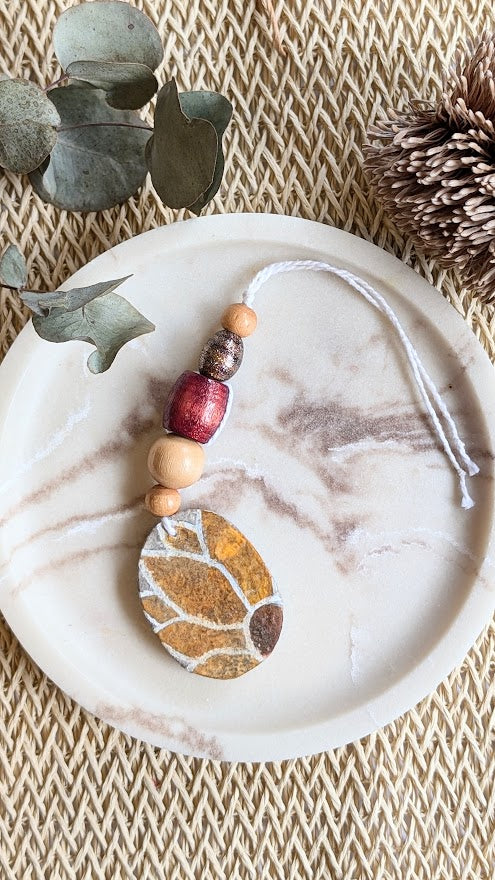 Decorative hanging ornament with sunflower design on a marble surface.