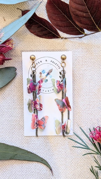 andmade watercolour butterfly paper earrings with chain drops, displayed on a Paper & Palette Studio card. Surrounded by native Australian foliage on a neutral fabric background.