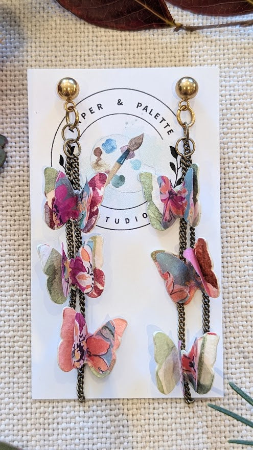 Elowen Collection butterfly earrings photographed flat with natural lighting. Styled with deep red and pink Australian native leaves for a botanical look.