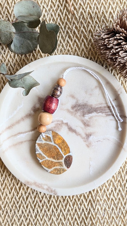Decorative hanging ornament with sunflower design on a marble surface.