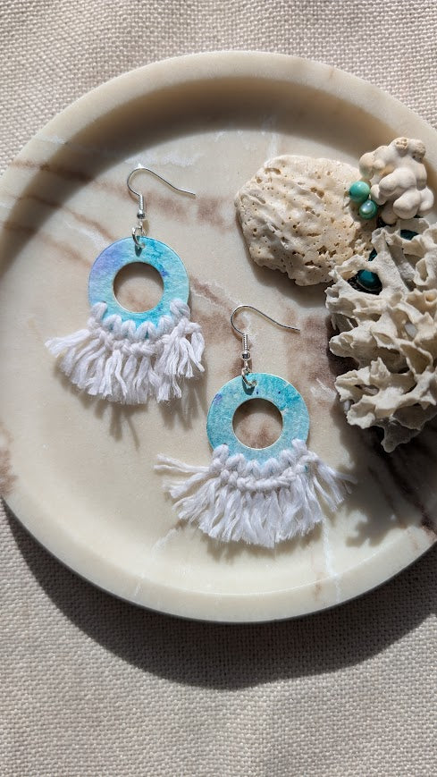 Pair of earrings with turquoise and white circular design on a shell and coral background