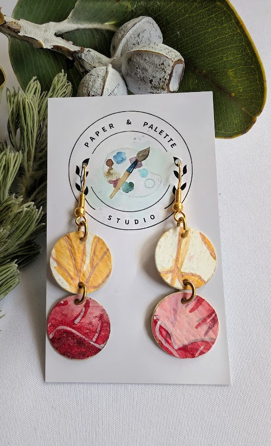 Pair of earrings with colorful circular designs on a 'Paper & Palette Studio' card.